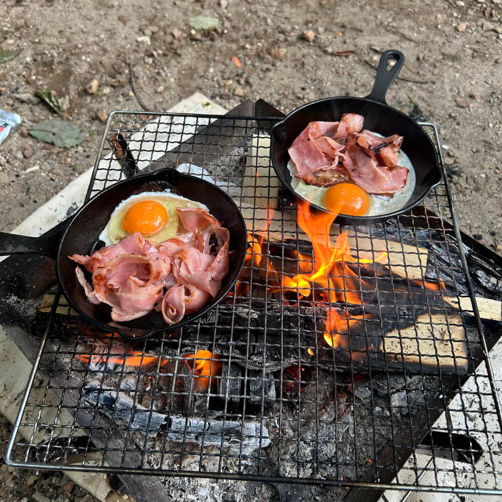 焚き火の直火でスキレットを使い調理するハウル飯(ベーコンエッグ)