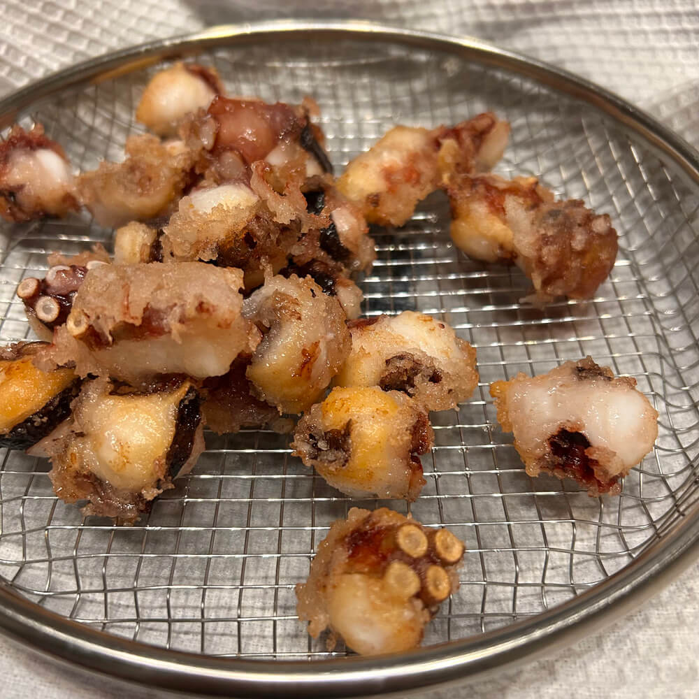 ザルに盛られた揚げたてのタコの唐揚げ